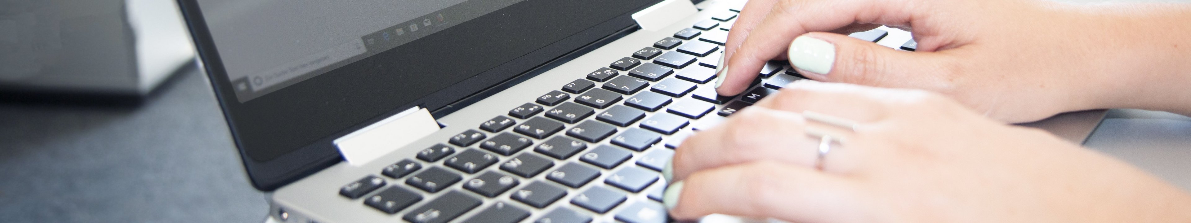 Hände die auf einer Laptoptastatur tippen